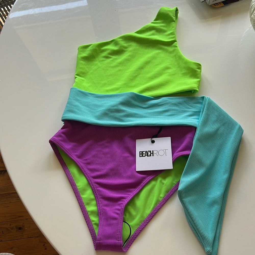 Beach Riot one-piece swimsuit in neon green, purple, and blue, Carli style